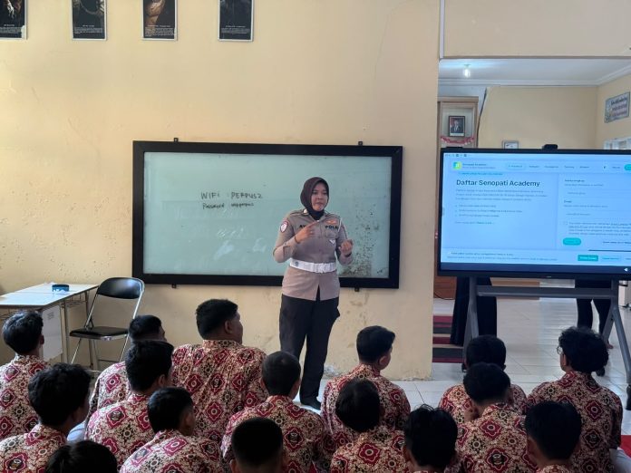 Seorang polisi wanita memberikan sosialisasi kepada sekelompok siswa di dalam ruangan